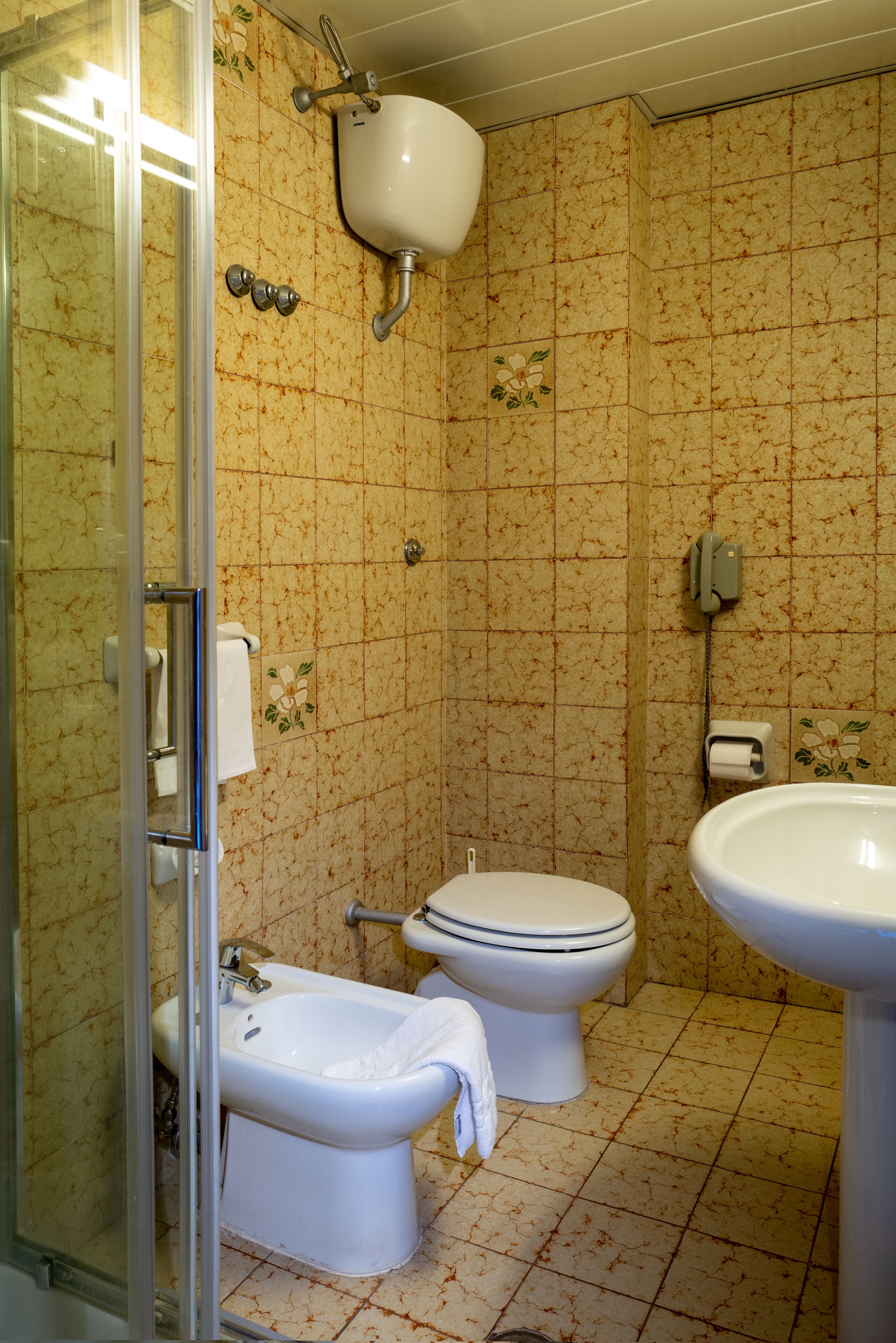 A bathroom with a shower, toilet, bidet, and sink.