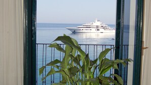 A balcony with a potted plant, a view of the sea, and a cruise ship in the distance. - Hotel Lido Mediterranee (Taormina)