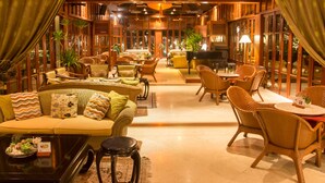 A spacious lounge area with wicker furniture, a piano, and a dining area with yellow chairs. - Furama Resort Danang (Da Nang)