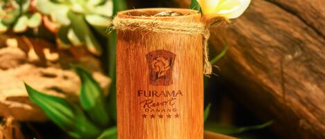 A bamboo container with a flower garnish, placed on a wooden surface with a white cloth underneath.