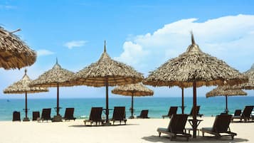 Praia particular, areia branca, espreguiçadeiras, guarda-sóis