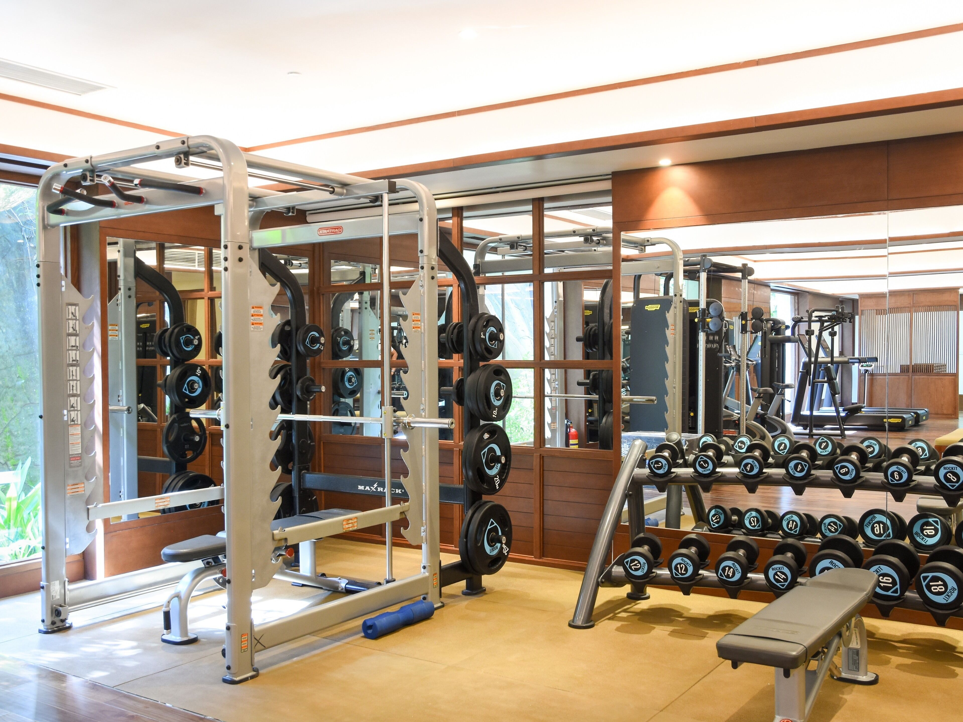 A gym with weightlifting equipment, benches, and dumbbells.