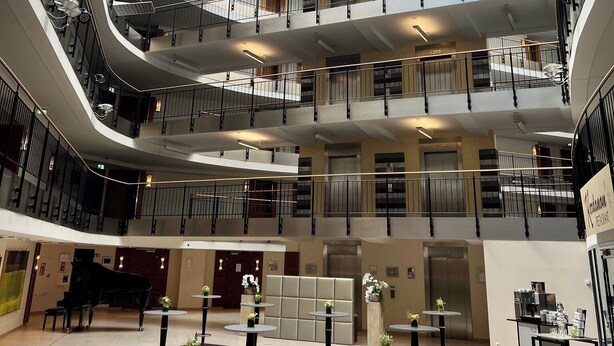 A multi-level atrium with a glass ceiling, multiple balconies, and a grand piano in the lower level. - Dorint Hotel Esplanade Jena (Jena)