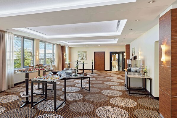 Un vestíbulo de hotel con alfombra estampada, ventanas amplias y luminarias modernas.