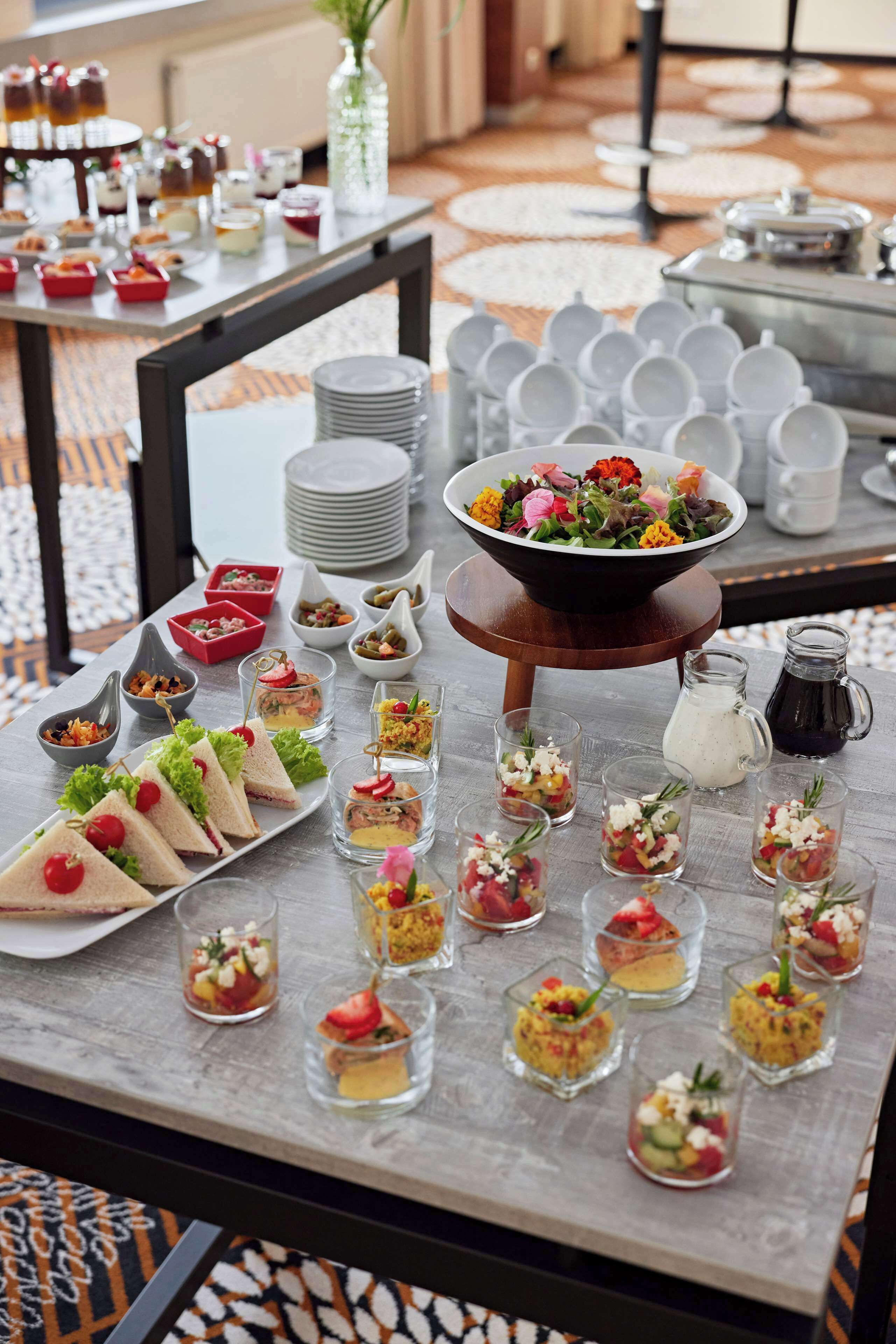 A buffet table with various food items and a bowl of salad.