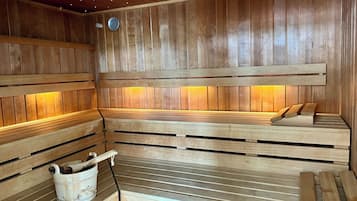 A sauna with wooden benches and a bucket of towels.