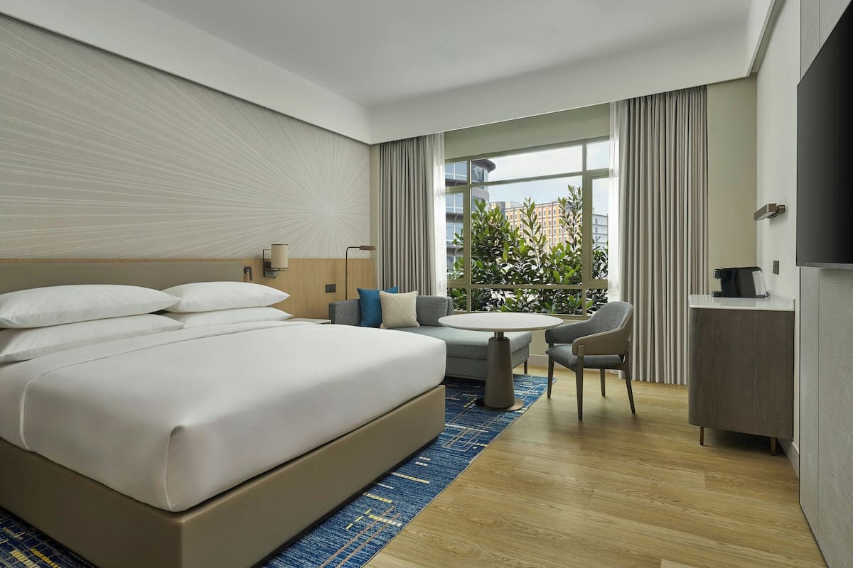 Een moderne hotelkamer met een groot bed, een klein rond tafeltje, een bank en een bureau.
