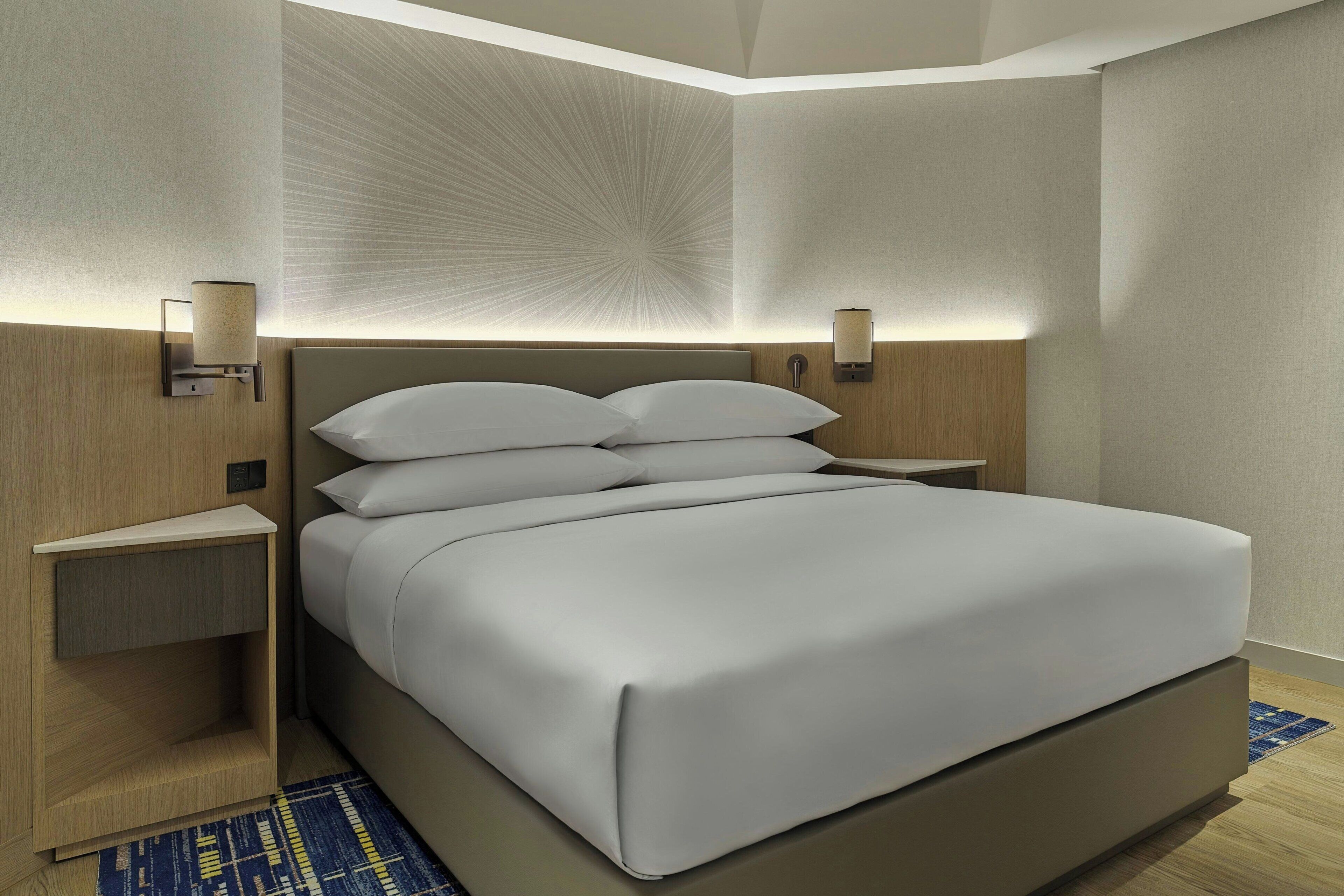Ein modernes Hotelzimmer mit einem großen Bett, Nachttischen und Wandlampen.