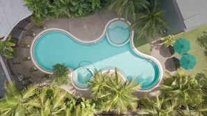 An aerial view of a swimming pool with a heart-shaped design, surrounded by palm trees and shaded by umbrellas. - Petaling Jaya Marriott Hotel (Petaling Jaya)