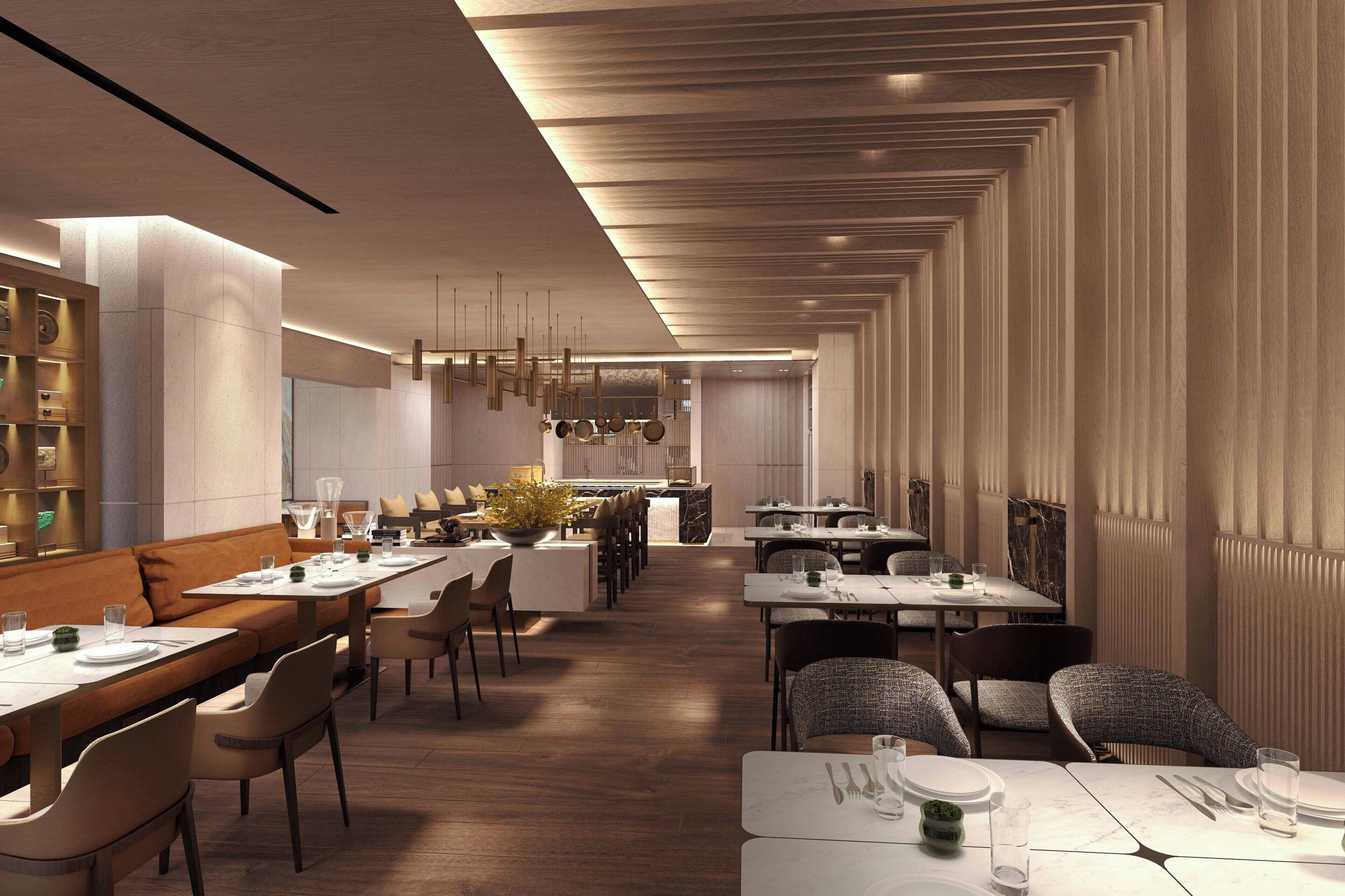 A modern restaurant with long tables, cushioned seating, and pendant lighting.