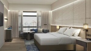 A modern hotel room with a large bed, a sofa, a small table, and a city view. - Petaling Jaya Marriott Hotel (Petaling Jaya)
