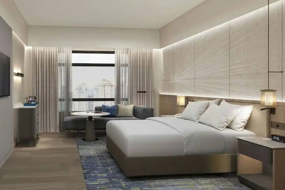 Een moderne hotelkamer met een groot bed, een bank, een tafeltje en uitzicht op de stad.