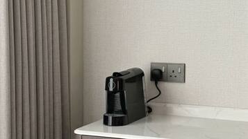 Una cafetera sobre una encimera blanca junto a un enchufe de pared.