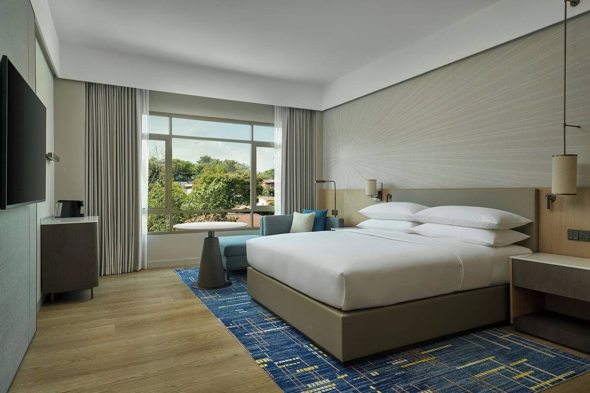 Een moderne hotelkamer met een groot bed, een klein tafeltje, een bank en een televisie.