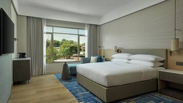 Una habitación de hotel moderna con una cama grande, una mesita, un sofá y un televisor.