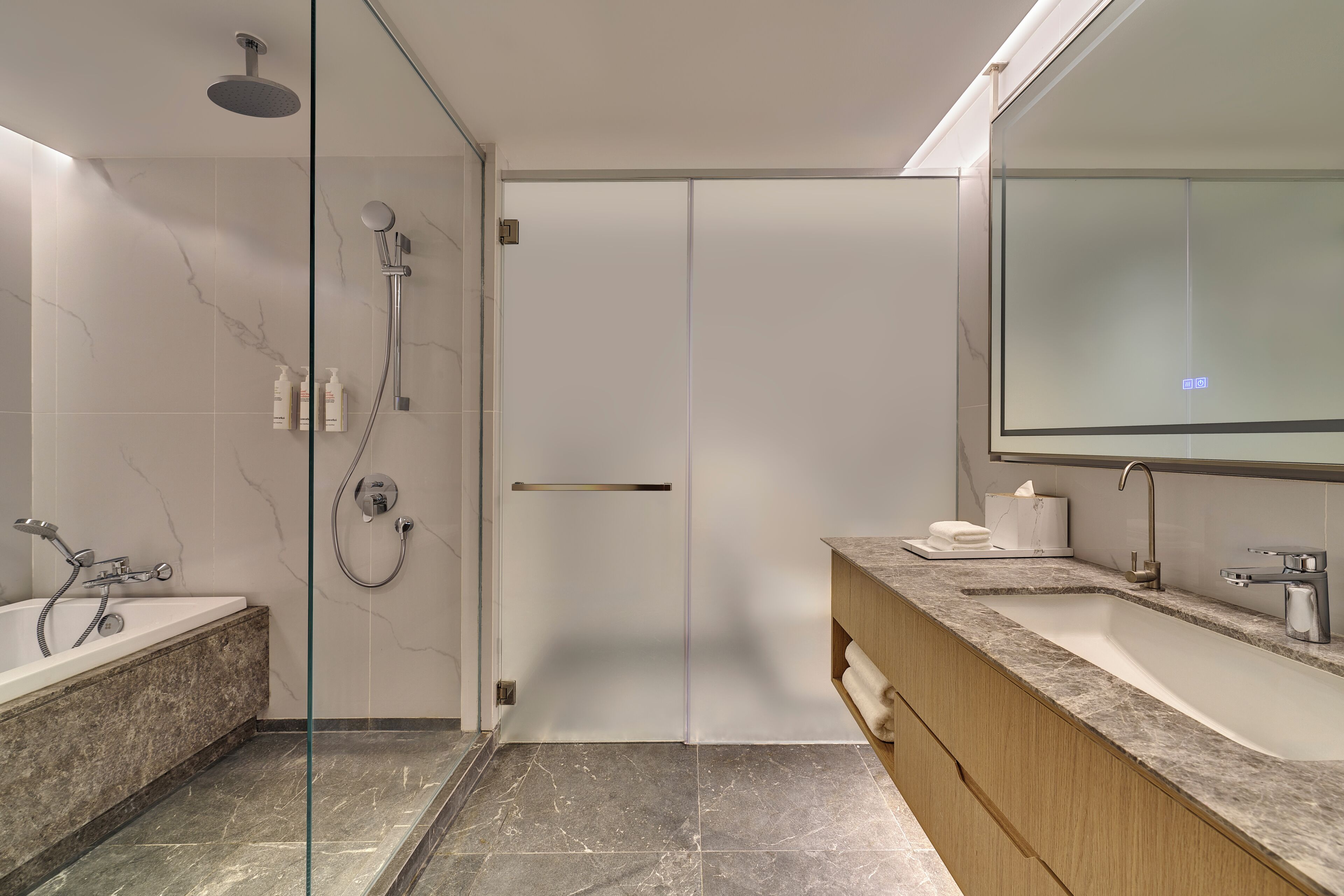 Un baño moderno con cabina de ducha de vidrio, bañera, tocador con lavabo y un espejo grande.