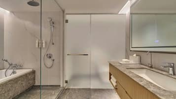 Een moderne badkamer met een douche met glazen wand, een bad, een wastafel met een marmeren blad en een grote spiegel.