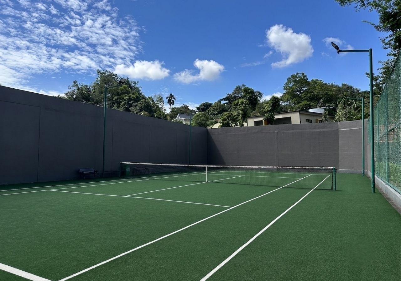 An indoor tennis court with a net, surrounded by walls and a fence.