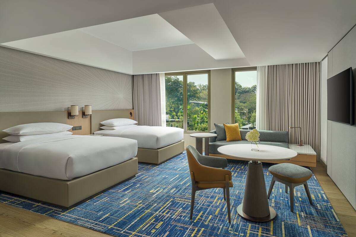 Een hotelkamer met twee bedden, een bank, een kleine tafel en een televisie.