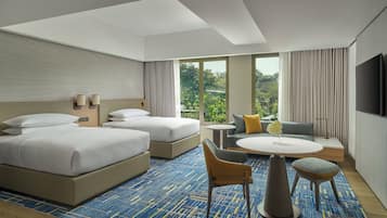 A hotel room with two beds, a sofa, a small table, and a TV.