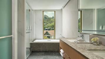 A modern bathroom with a large window, a bathtub, a vanity with a mirror, and a sink.
