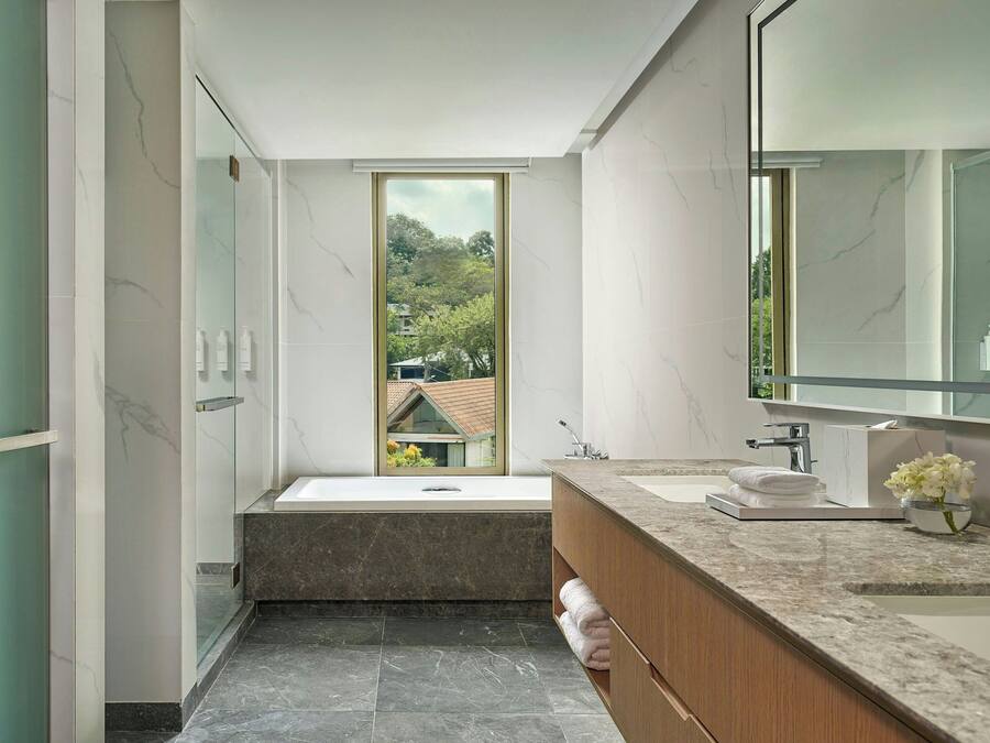 A modern bathroom with a large window, a bathtub, a vanity with a mirror, and a sink.
