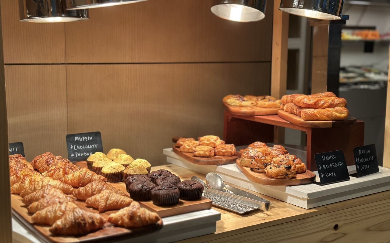 Mostrador de panadería con diversos pasteles y muffins, incluyendo sabores a chocolate y plátano.