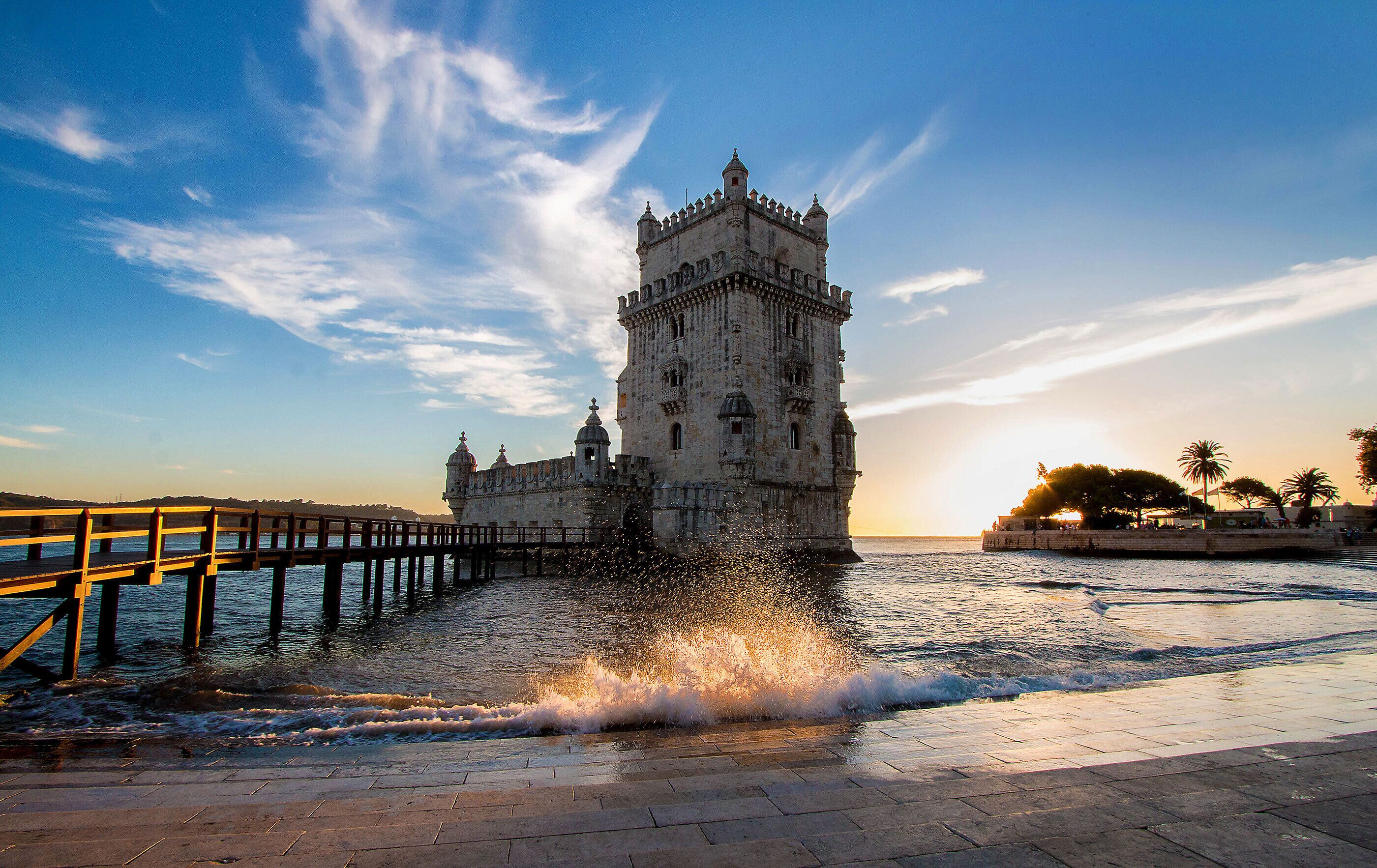 Uma torre histórica junto a uma orla marítima com um cais de madeira.