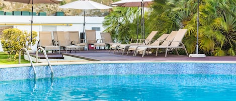 Una piscina al aire libre, sillones reclinables de piscina