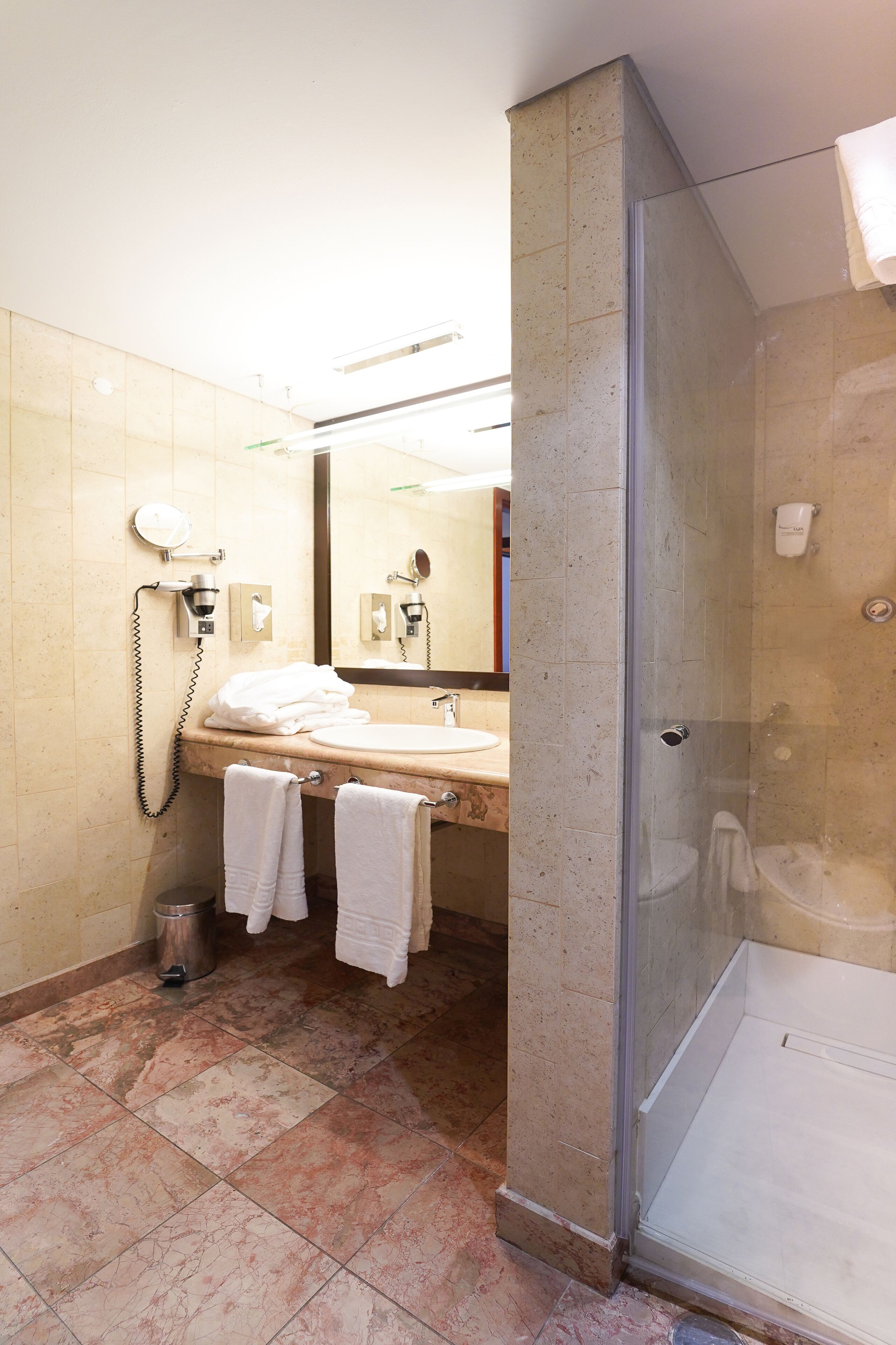 Un baño con lavamanos, espejo y ducha.