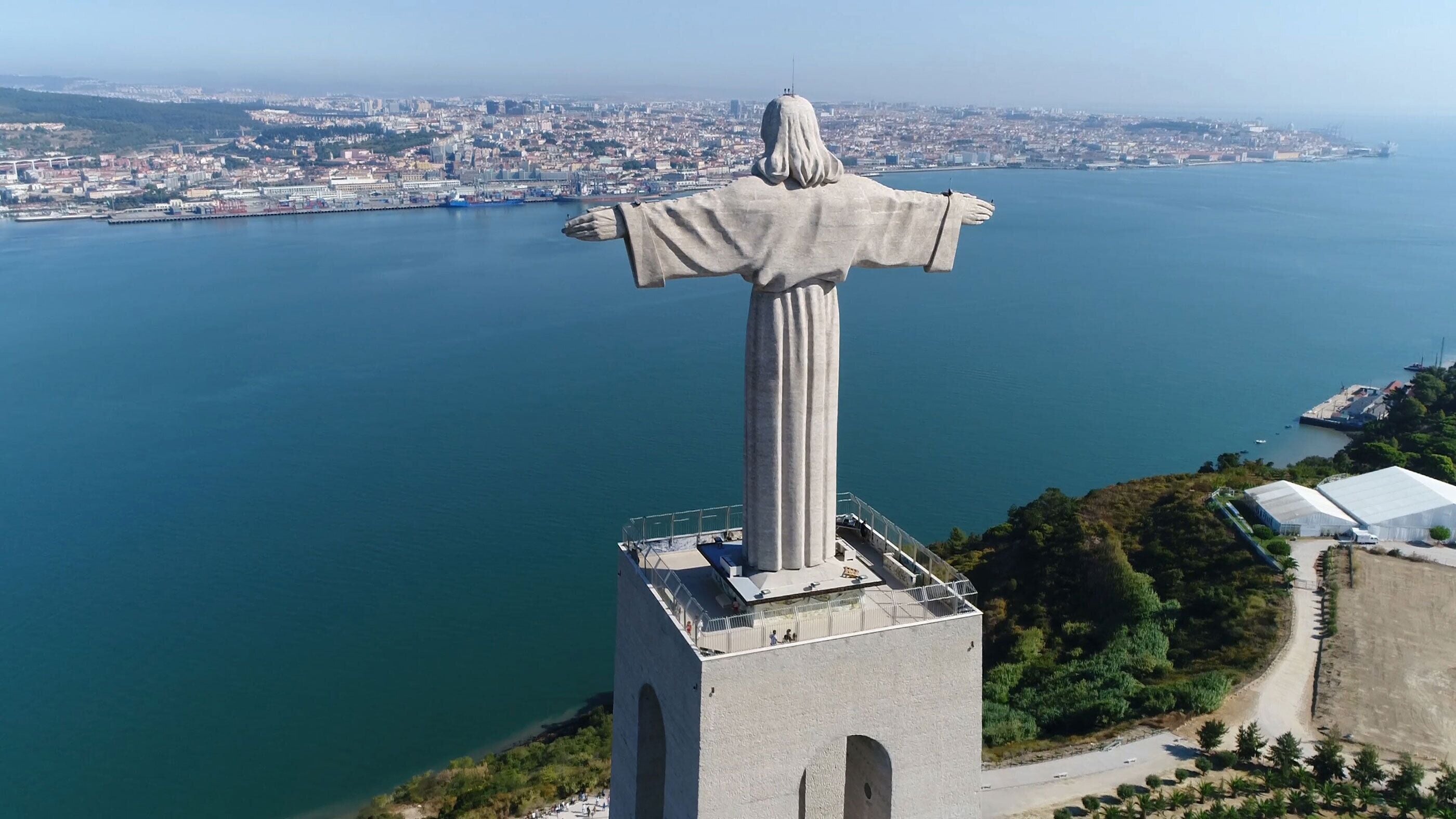 A statue on a pedestal overlooking a coastal cityscape.