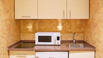 A compact kitchen with a microwave, sink, and built-in dishwasher.