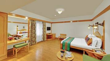 A hotel room with a bed, desk, chair, and a small table with a bowl of fruit.