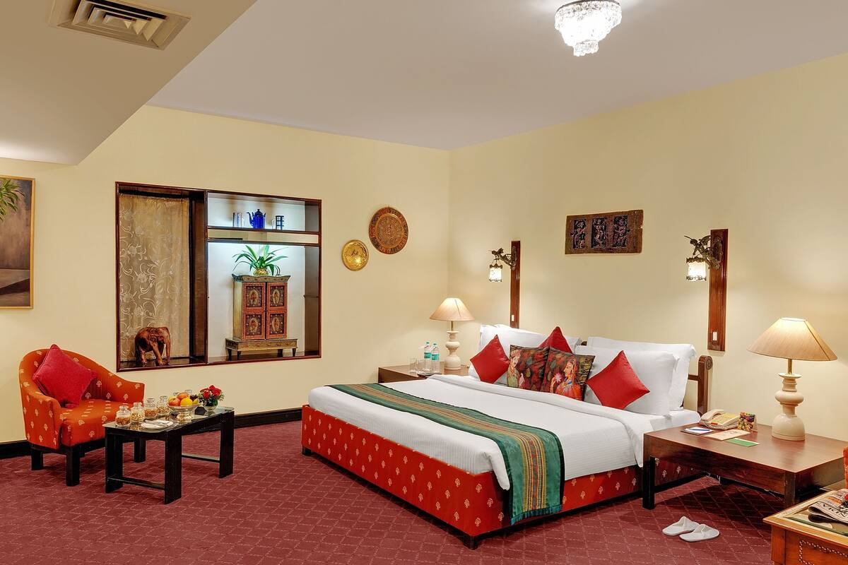 A hotel room with a bed, a chair, a table, and a nightstand.
