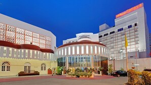 A hotel with a modern facade, large windows, and a well-maintained garden area. - Ambassador Pallava (Chennai)