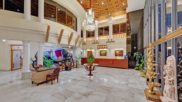 A grand lobby with marble floors, a chandelier, a reception desk, and a statue. - Ambassador Pallava (Chennai)