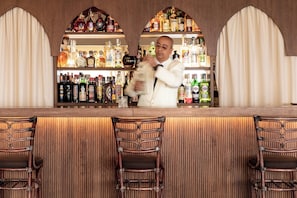 A bar with a wooden counter, multiple liquor bottles, and wicker chairs. - Mezzatorre Hotel & Thermal Spa (Forio)