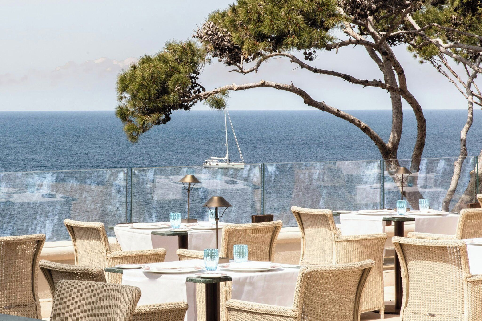 Possibilité de déjeuner ou dîner en plein air, avec des chaises et des tables en osier, offrant une vue sur la mer.