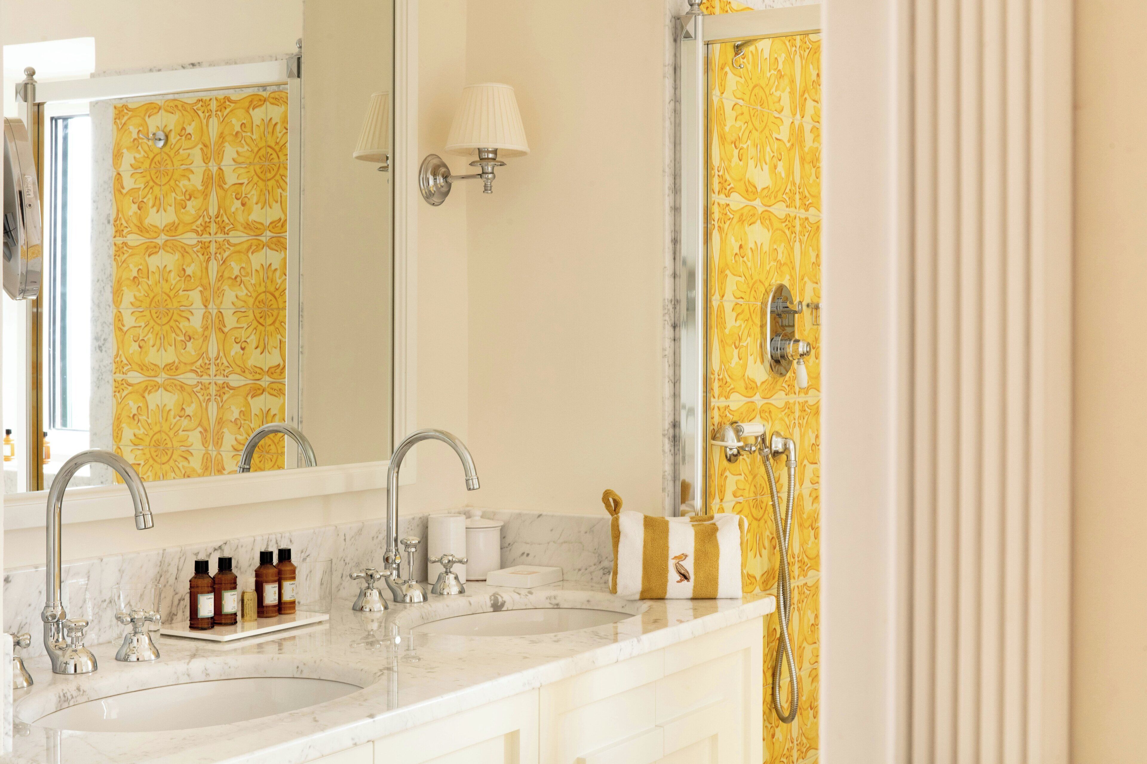 A bathroom with a double sink, a mirror, a towel rack, and a shower with a glass door.