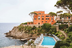 A coastal hotel with a swimming pool, lounge chairs, and a castle-like building. - Mezzatorre Hotel & Thermal Spa (Forio)