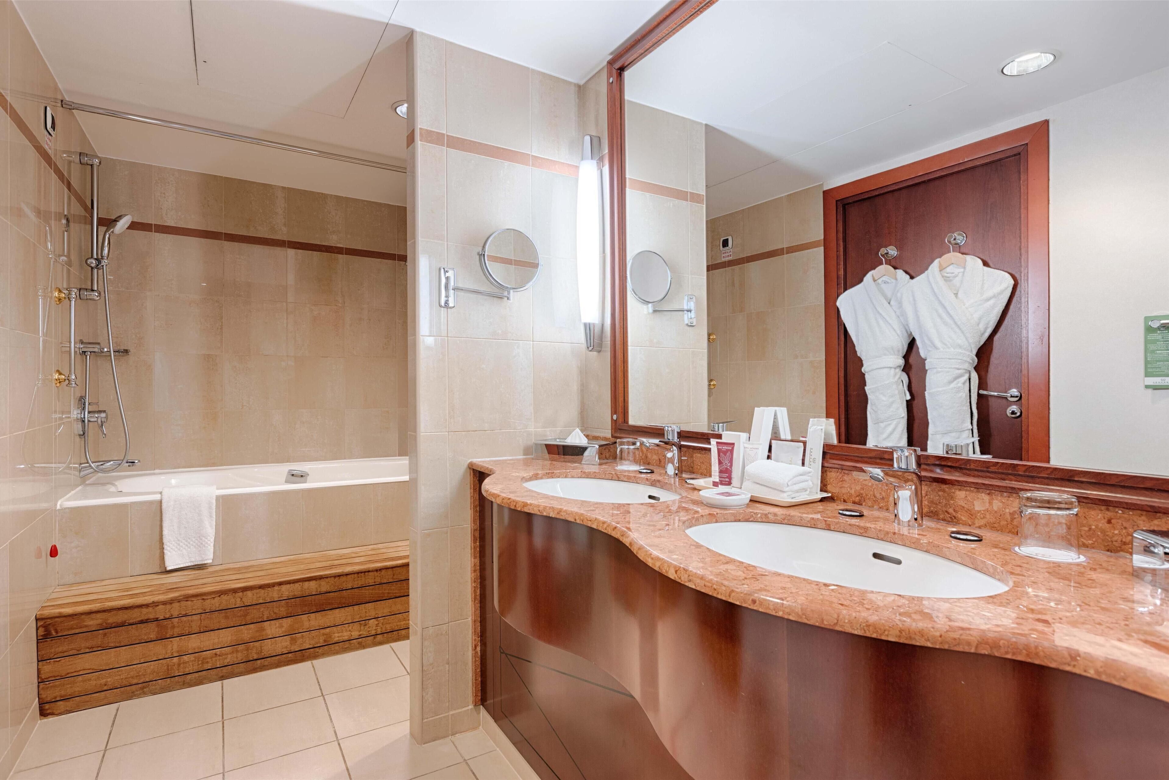 Un baño moderno con bañera, dos lavamanos, un espejo grande y ducha.