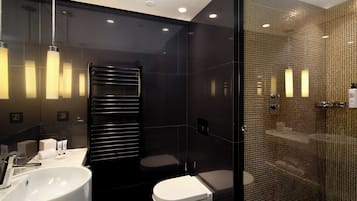 A modern bathroom with a large white sink, a toilet, and a glass-enclosed shower area.