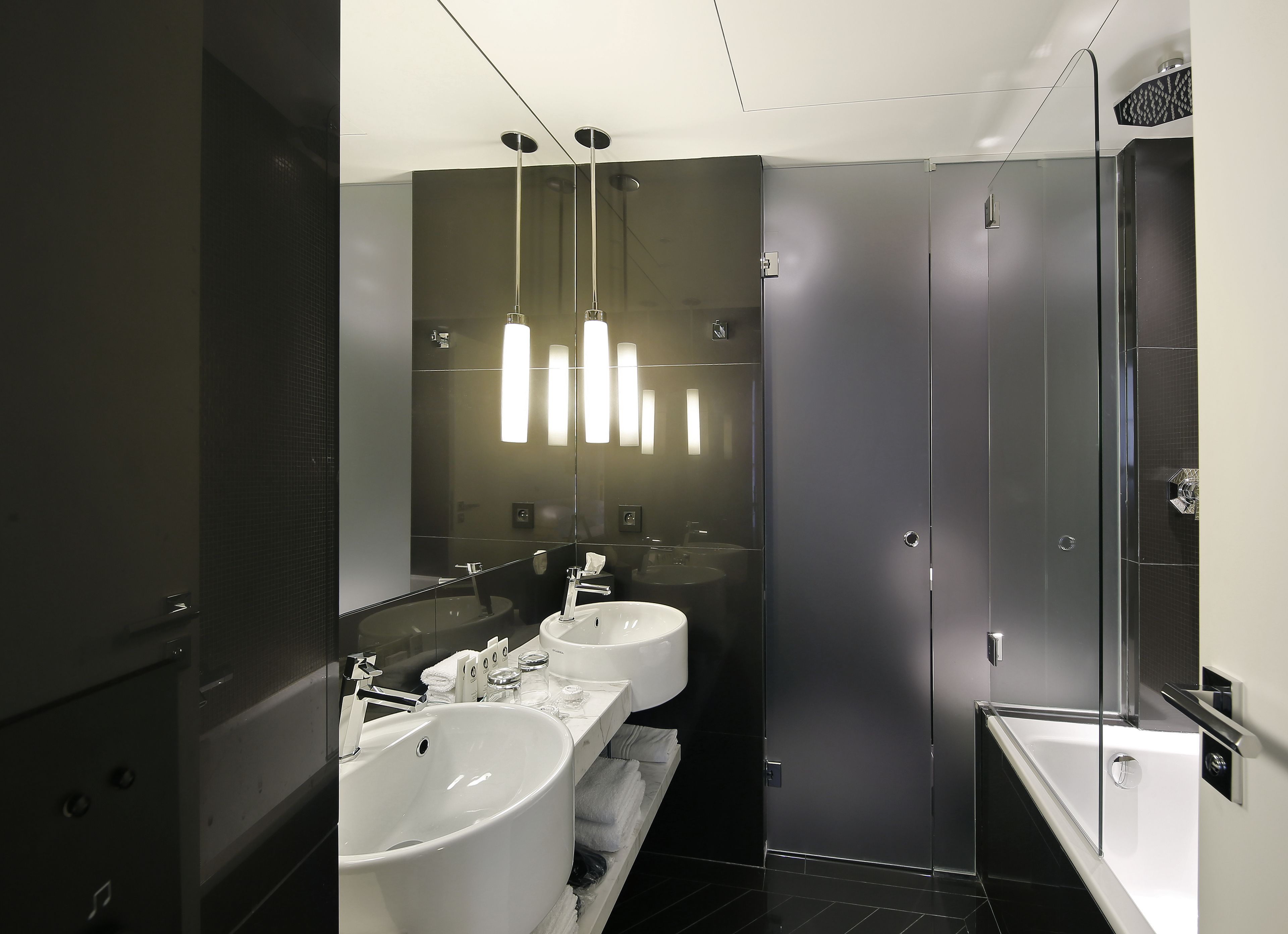 Une salle de bain moderne avec deux lavabos, un grand miroir et une douche à l’italienne.