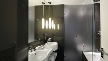 A modern bathroom with two sinks, a large mirror, and a walk-in shower.