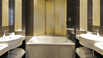 Un baño moderno con dos lavamanos, una bañera y un espejo grande.