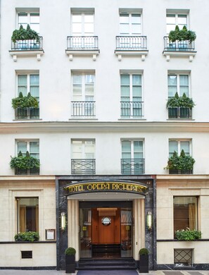 A multi-story building with a grand entrance, featuring a sign that reads "HOTEL OPERA RICHEPANISL".
