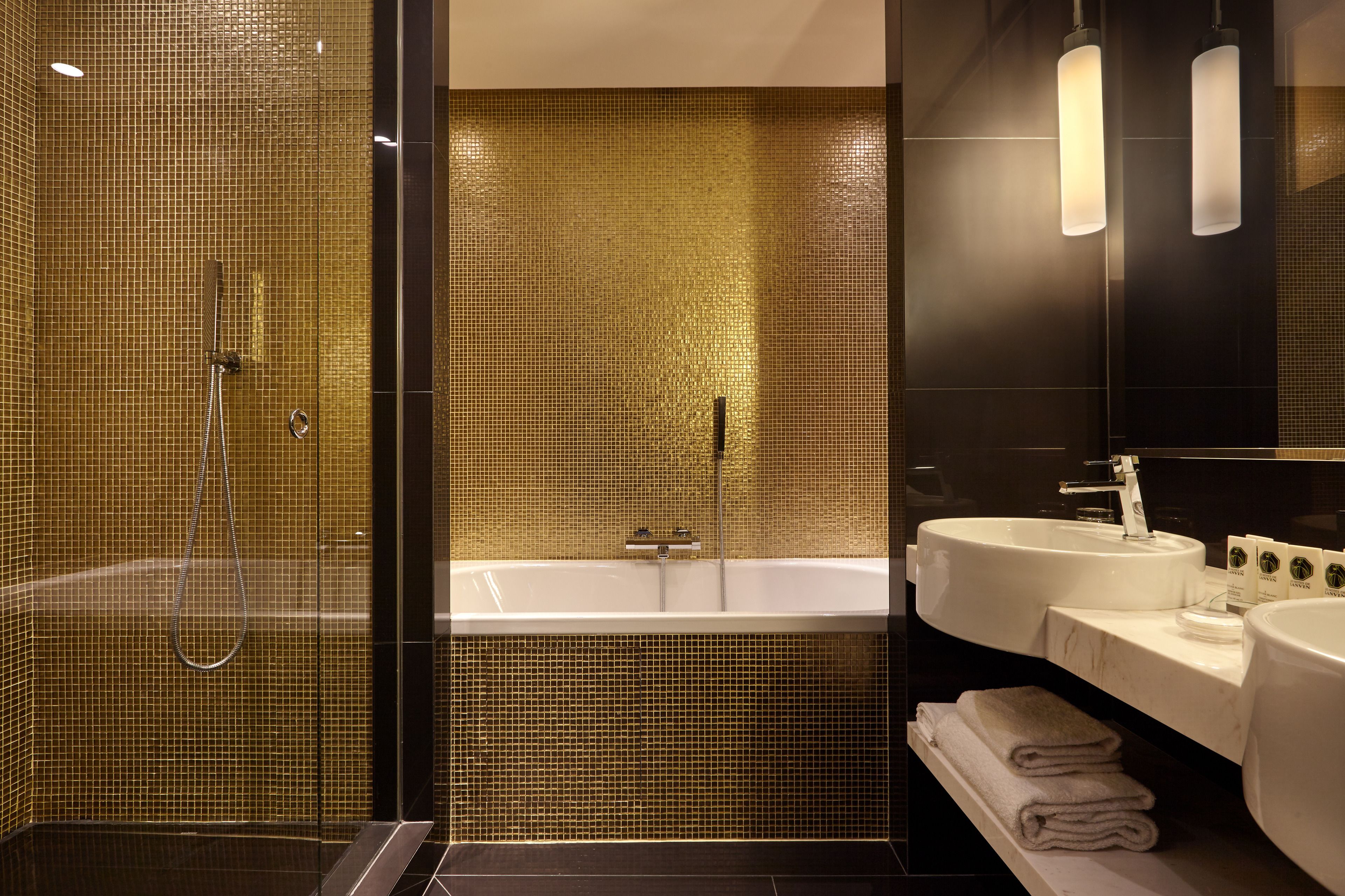 A modern bathroom with a glass-enclosed shower, a freestanding bathtub, and two sinks with a large mirror above.