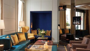 A modern hotel lobby with a blue accent wall, comfortable seating, and a bar area.