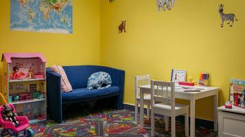 Un cuarto de juegos infantil con un mapa mundial, peluches, una casa de muñecas y un tapete de juegos colorido.