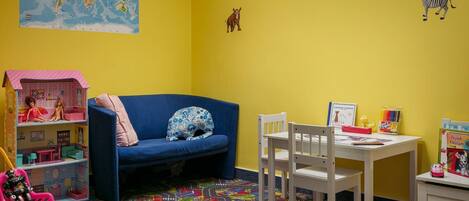 A child's playroom with a world map, stuffed animals, a dollhouse, and a colorful play mat.